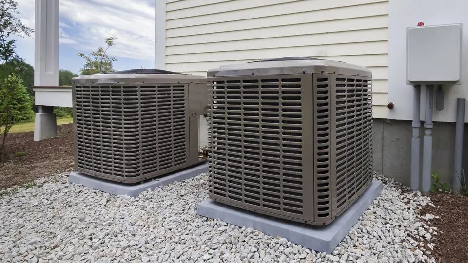 Two outdoor AC condensers on a gravel pad